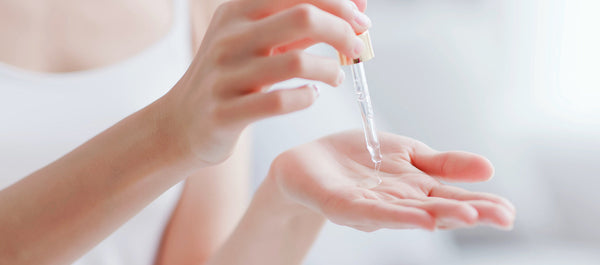 Woman layering hyaluronic acid and CoQ10 serums as part of her skincare routine