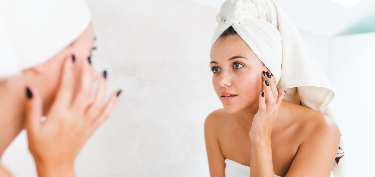 woman performing daily skincare routine in mirror