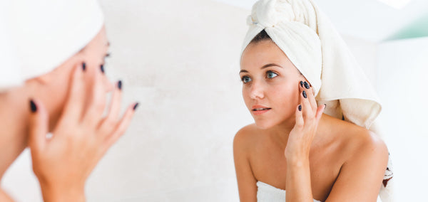woman performing daily skincare routine in mirror